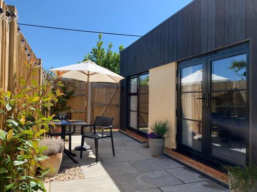 a patio with an umbrella and a table and chairs at The Burrow at Tankerton in Whitstable