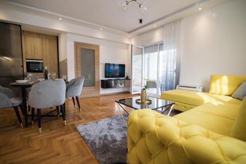 a living room with a yellow couch and a dining room at July in Trebinje