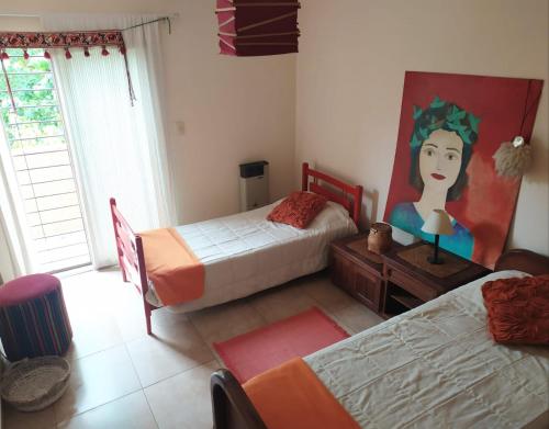 1 dormitorio con 2 camas y una pintura de una mujer en El Agasajo, Córdoba Capital casa de 3 habitaciones, en Córdoba