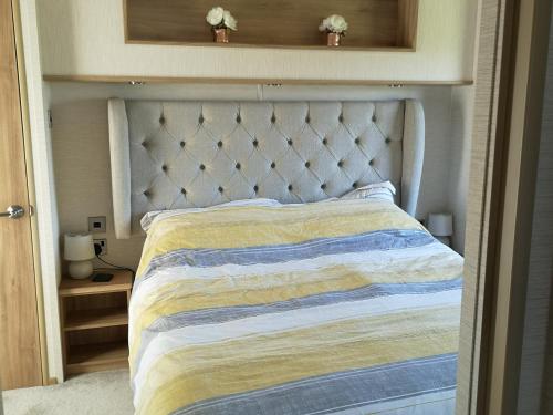 a bedroom with a bed with a white headboard at Top Spec Caravan - Stunning sea views across bay in Swanage