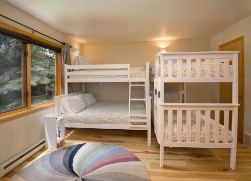 two white bunk beds in a room with a window at Greenbrier Townhouse 36 in Avon