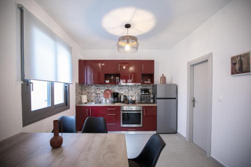 a kitchen with red cabinets and a table and a refrigerator at Amarynthos Maisonettes in Amarinthos