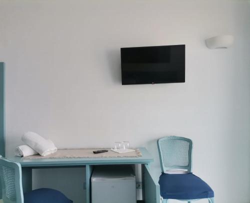 a desk with two chairs and a television on a wall at Residenz e Ristorante da Mimì in Ischia