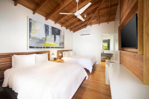 a bedroom with two beds and a flat screen tv at Ibagari Boutique Hotel in Roatan