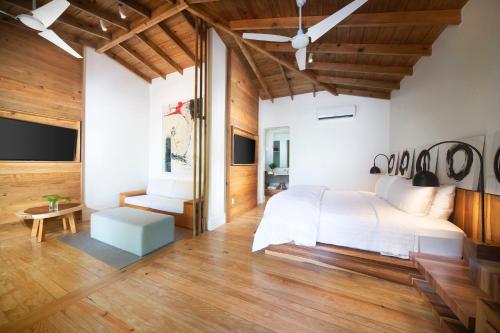 a bedroom with a white bed and wooden floors at Ibagari Boutique Hotel in Roatan