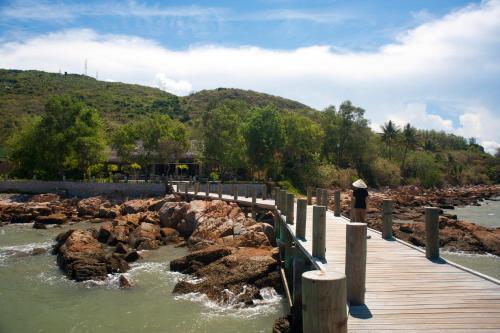 a wooden bridge over a river with rocks at L'Alya Ninh Van Bay in Ninh Van Bay