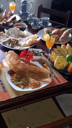 a table with plates of food and fruit on it at Jal,Min Homestay in Kandy