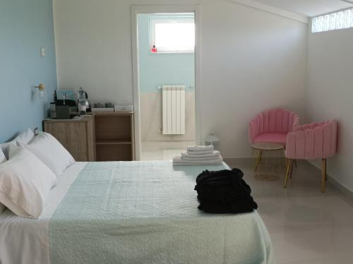 1 dormitorio con 1 cama grande y sillas rosas en La Suite della casa bianca, en San Salvatore Telesino