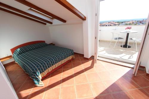 a bedroom with a bed and a balcony with a table at Apartments Elida in Rovinj