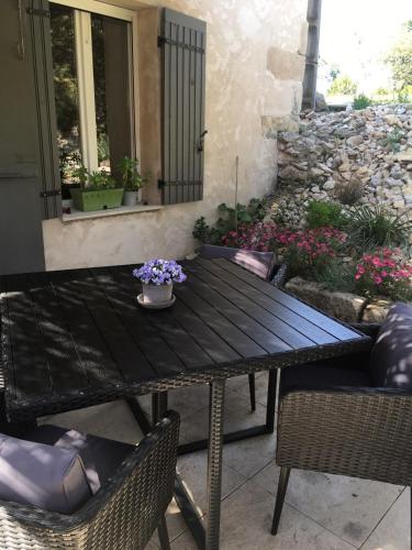 einen Holztisch mit Stühlen und Blumen auf einer Terrasse in der Unterkunft Juste derrière chez nous in Boulbon