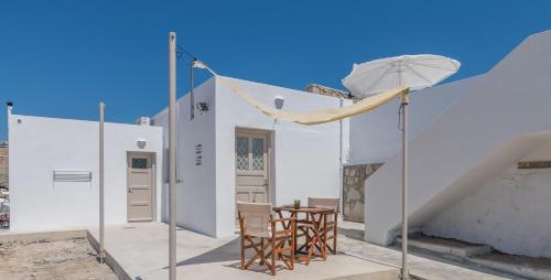 a white house with chairs and a table and an umbrella at Amato in Mandrakia