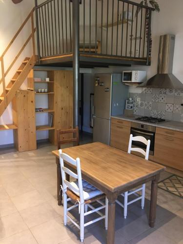 a kitchen with a wooden table and white chairs at Juste derrière chez nous in Boulbon