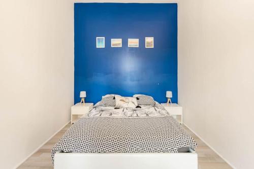 un lit dans une chambre avec un mur bleu dans l'établissement Appart'LH - Stationnement gratuit - B'PAM, au Havre