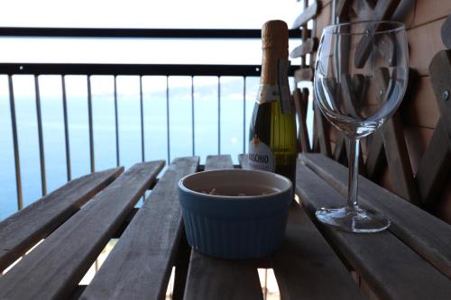 a wooden table with a wine glass and a bowl at Una Conchiglia sul Mare Attico vista Portofino in Zoagli
