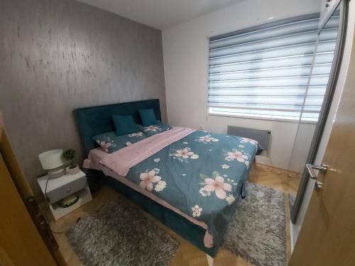 a bedroom with a bed with a blue comforter with flowers at Dora Lux & Free Indoor Parking in Vrnjačka Banja