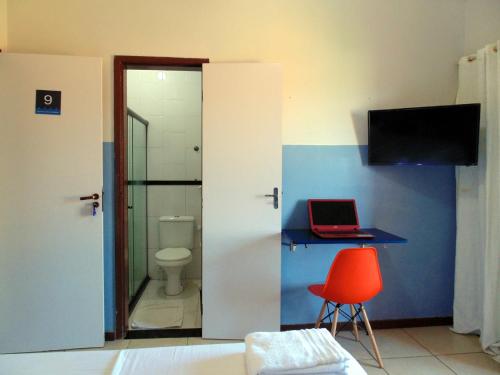 a bathroom with a toilet and a laptop on a desk at FAROL BEACH Suítes in Salvador