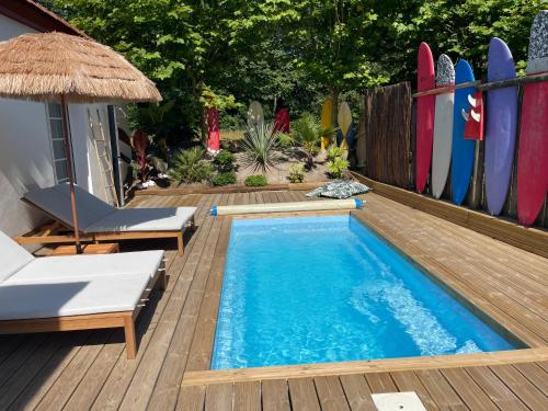 a swimming pool next to a deck with surfboards at Villa avec Piscine à 5 minutes de l’océan in Bidart