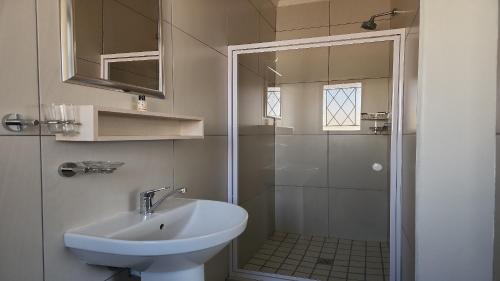 a white bathroom with a sink and a shower at Avanti Guest Lodge in Vredenburg