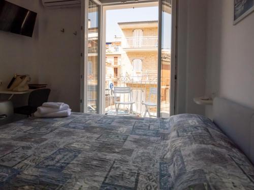 a bedroom with a large bed and a large window at Camere Casa Azzurra in Porto San Giorgio