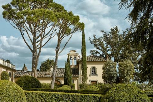 a house with trees and bushes in front of it at COMO Castello Del Nero in Tavarnelle in Val di Pesa