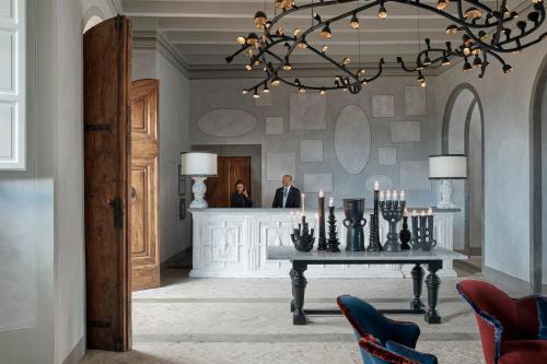 a room with a table and a man in a mirror at COMO Castello Del Nero in Tavarnelle in Val di Pesa