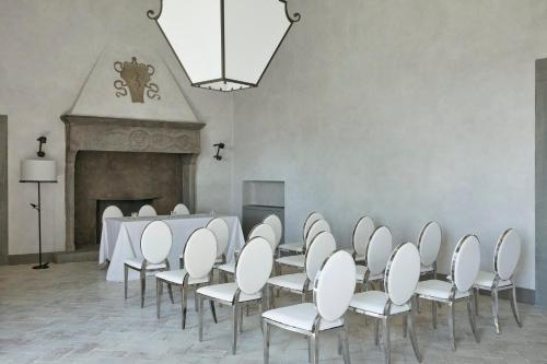 a room with a table and chairs and a fireplace at COMO Castello Del Nero in Tavarnelle in Val di Pesa