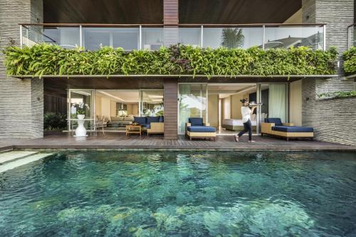 a woman taking a picture of a house with a swimming pool at COMO Uma Canggu in Canggu