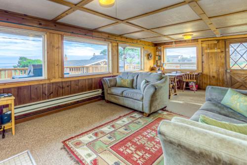 a living room with a couch and a table and windows at Elbow's Inn in Rockaway Beach