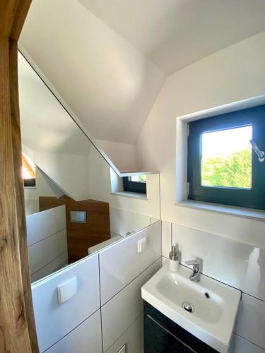 a white bathroom with a sink and a window at Osada Żywiec in Żywiec