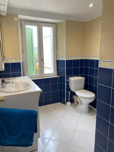 uma casa de banho em azulejos azuis com um WC e um lavatório em Highland sur Mer em Étables