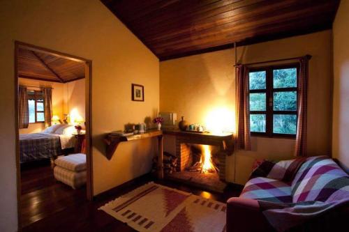 een woonkamer met een open haard en een slaapkamer bij Fazenda pedra selada in Visconde De Maua