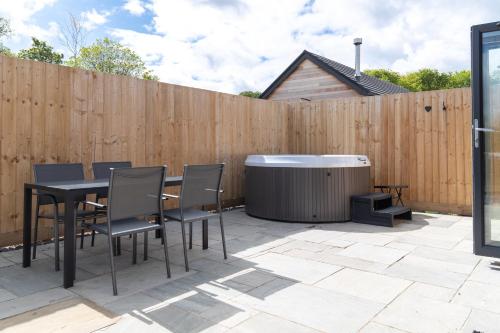 a patio with a table and chairs and a hot tub at Cedar Cottage in Tenby