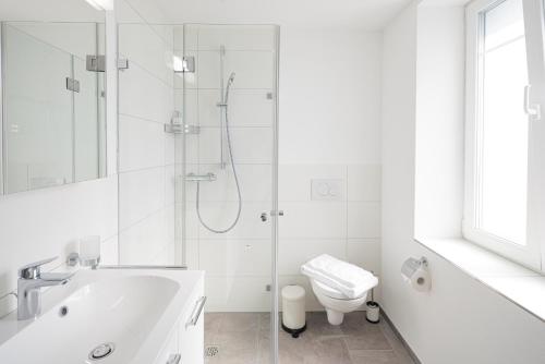 a white bathroom with a shower and a toilet at EH Apartments Saturn in St. Gallen