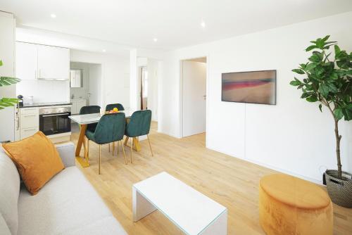 a white living room with a table and chairs at Steigerstrasse Apartments by VISIMO - Modern Living near OLMA & Hospital in St. Gallen