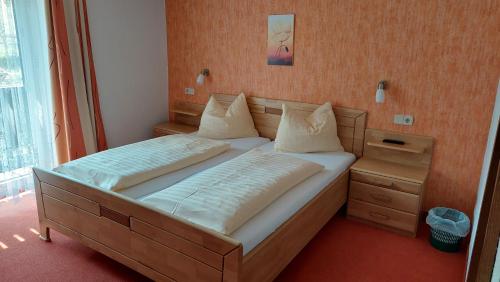 una camera da letto con un grande letto con lenzuola e cuscini bianchi di Hotel Pension Oswald a Mallnitz