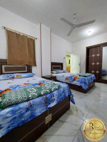 a bedroom with two beds and a ceiling fan at Royal Apartments in Matrouh in Marsa Matruh