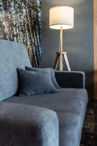 a living room with a blue couch and a lamp at OTTON-Charzykowy Bed&Restaurant in Chojnice