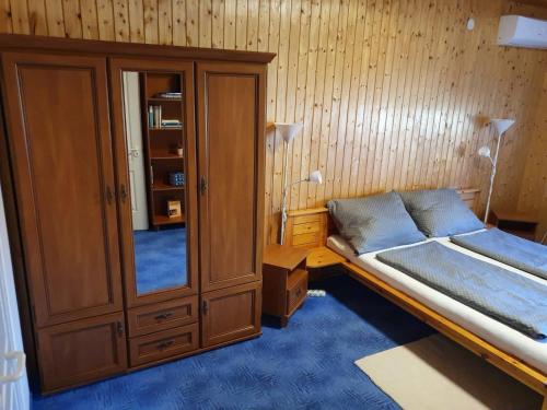 a bedroom with a bed and a wooden cabinet at Andris Apartman- Fonyód Tabán u 78 in Fonyód