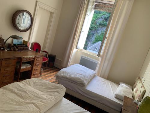 a bedroom with two beds and a desk and a window at La Maison in Saint-Béat