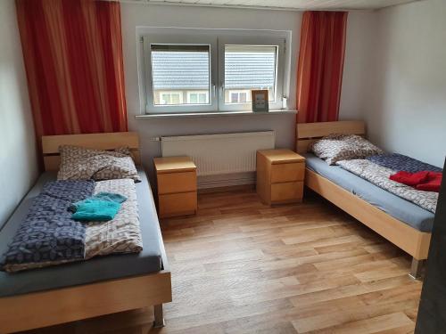a bedroom with two beds and a window with red curtains at HässelHof - 80qm Ferienwohnung im Zentrum von Bad Liebenwerda in Bad Liebenwerda