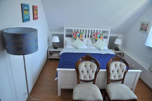 a bedroom with a white bed with two chairs at Apartament pod limbą in Gdynia