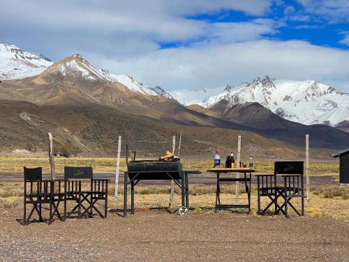 a grill and chairs with mountains in the background at La Horqueta in Malargüe