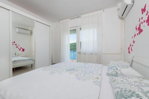 ein weißes Schlafzimmer mit einem großen Bett und einem Fenster in der Unterkunft Jadranka in Rabac