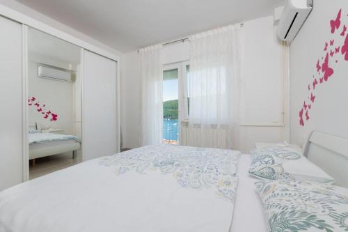 a white bedroom with a large bed and a window at Jadranka in Rabac