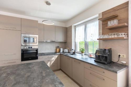 a kitchen with white cabinets and a black appliance at Aszúvilág Rezidencia with Sauna & Jacuzzi in Legyesbénye