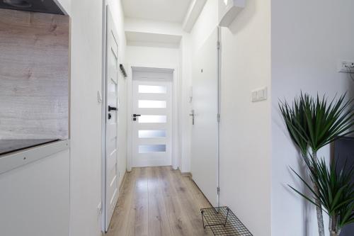 a hallway with white walls and a hardwood floor at Apartment Hotel STUD MB in Ostrava