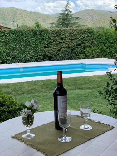 une bouteille de vin posée sur une table avec deux verres dans l'établissement Sierras VGB Bertone, à Villa General Belgrano