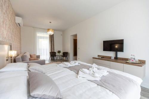 a large white bed in a room with a tv at Aszúvilág Rezidencia with Sauna & Jacuzzi in Legyesbénye