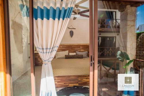 una puerta de cristal con cortina en una habitación en Lagoon Boutique Hotel - Luxury Chaman experience, en Tulum