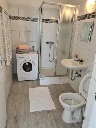 uma casa de banho com uma máquina de lavar roupa e uma máquina de lavar roupa. em Orchidea Apartment em Finkenstein